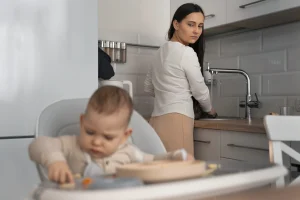 A caring nanny holding and soothing a newborn baby at home.